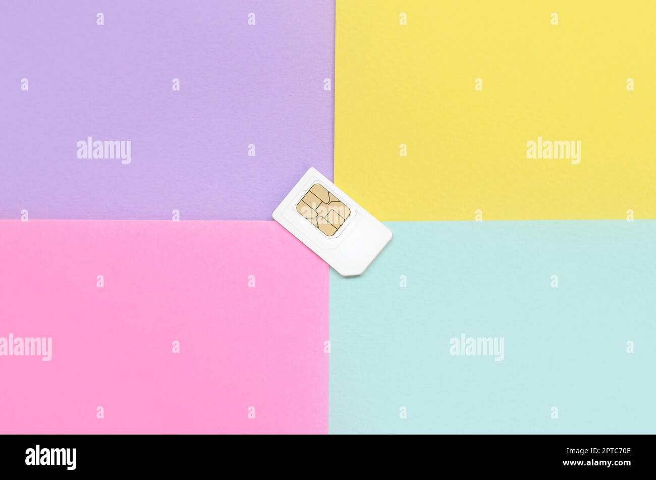 Subscriber identity module. New white SIM card on bright multicolor background. Minimal flat lay top view. Violet, pink, yellow and blue pastel colors Stock Photo