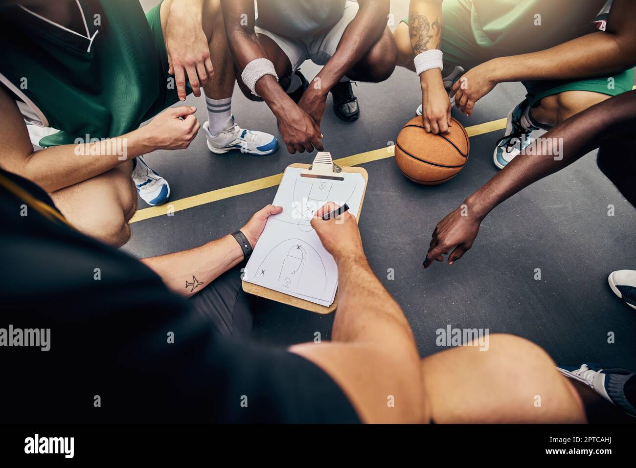 Basketball, strategy and team with a sports coach talking to a team while planning tactics on a clipboard and hands. Teamwork, fitness and exercise wi Stock Photo