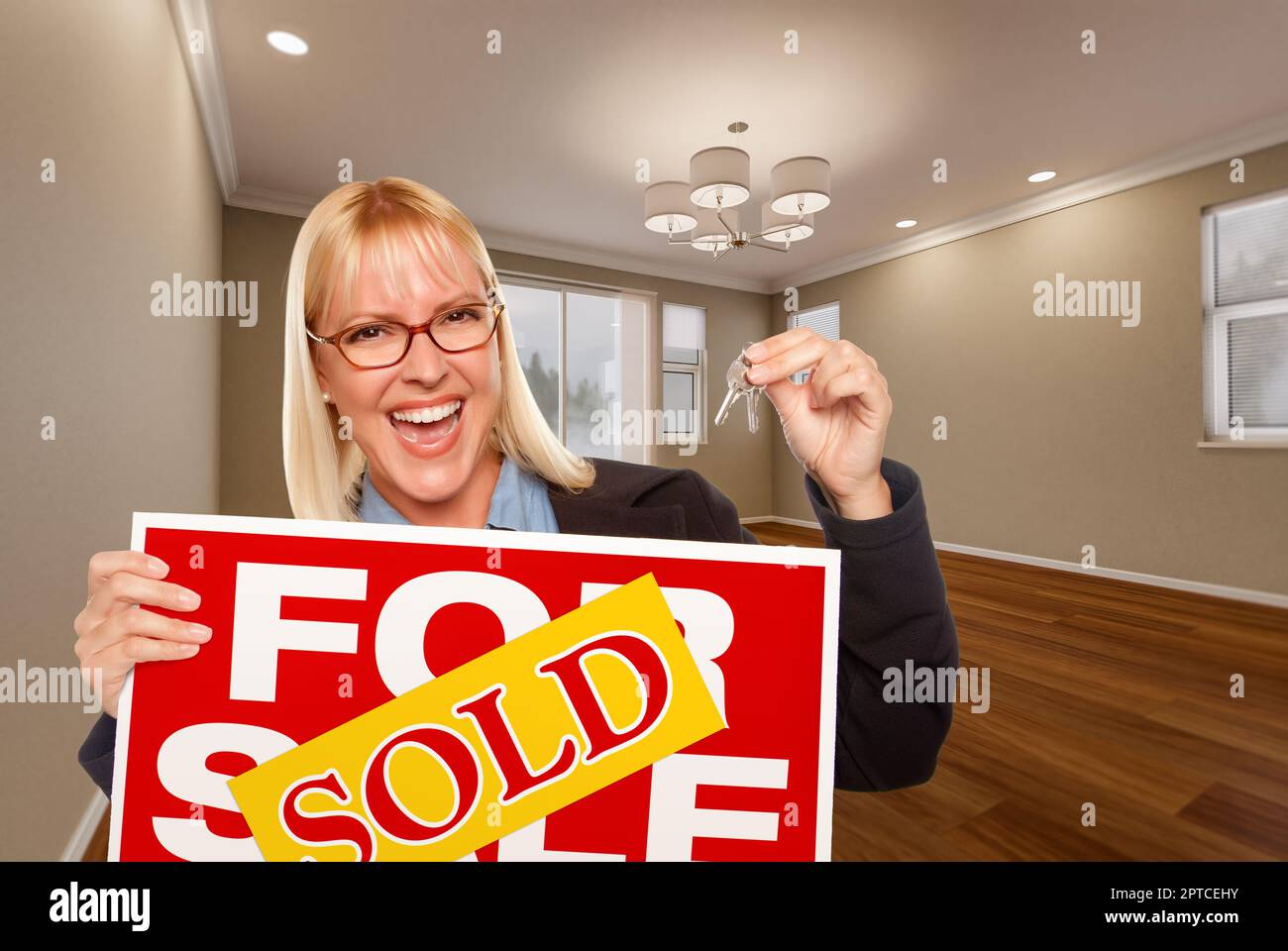 Attractive Young Woman with New Keys and Sold Real Estate Sign In Empty ...