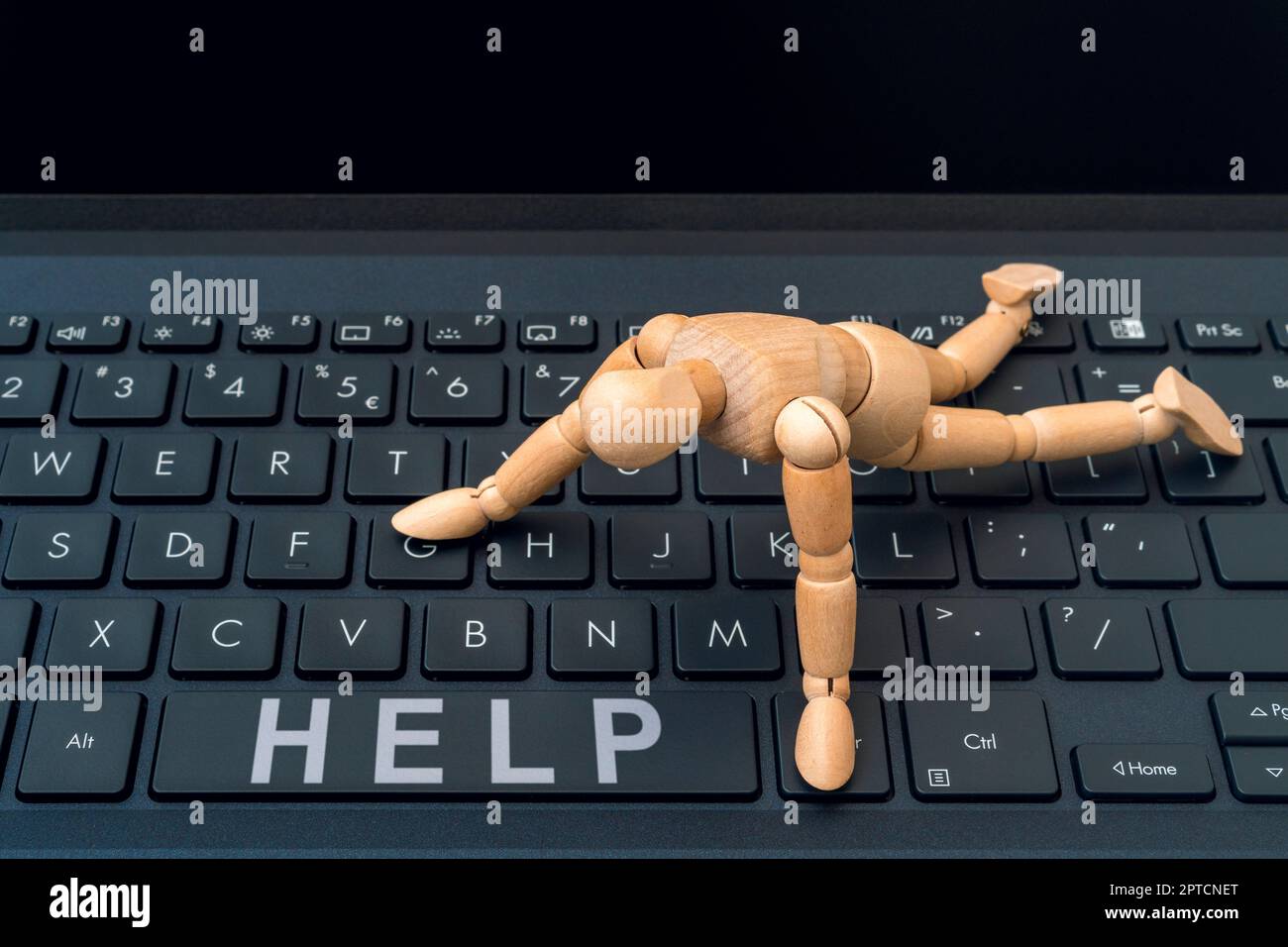 Online HELP button. Wooden dummy trying to reach HELP button on a computer keyboard. Stock Photo