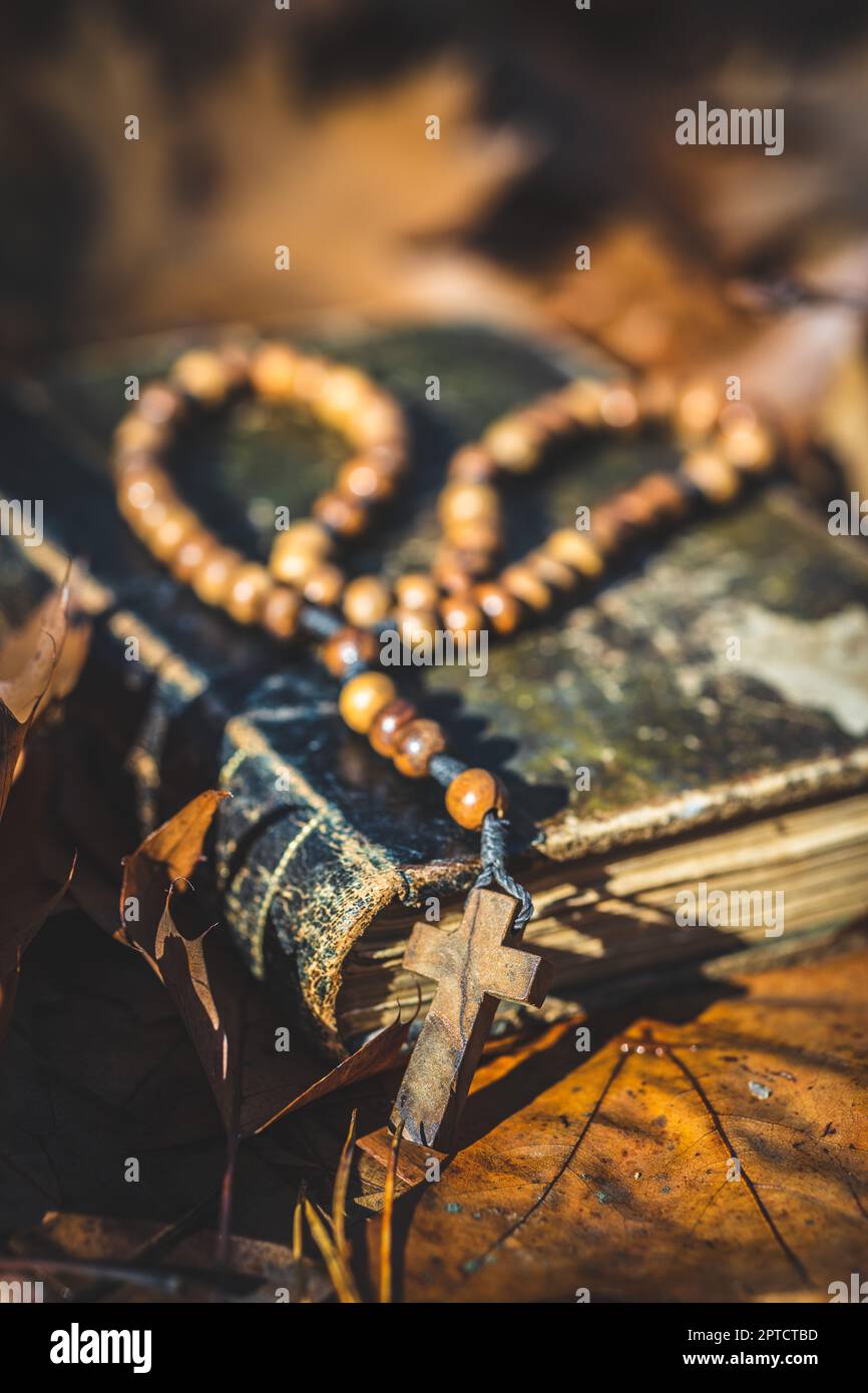 Wooden rosary beads and holy bible book lying on the autumn leaves. Stock Photo