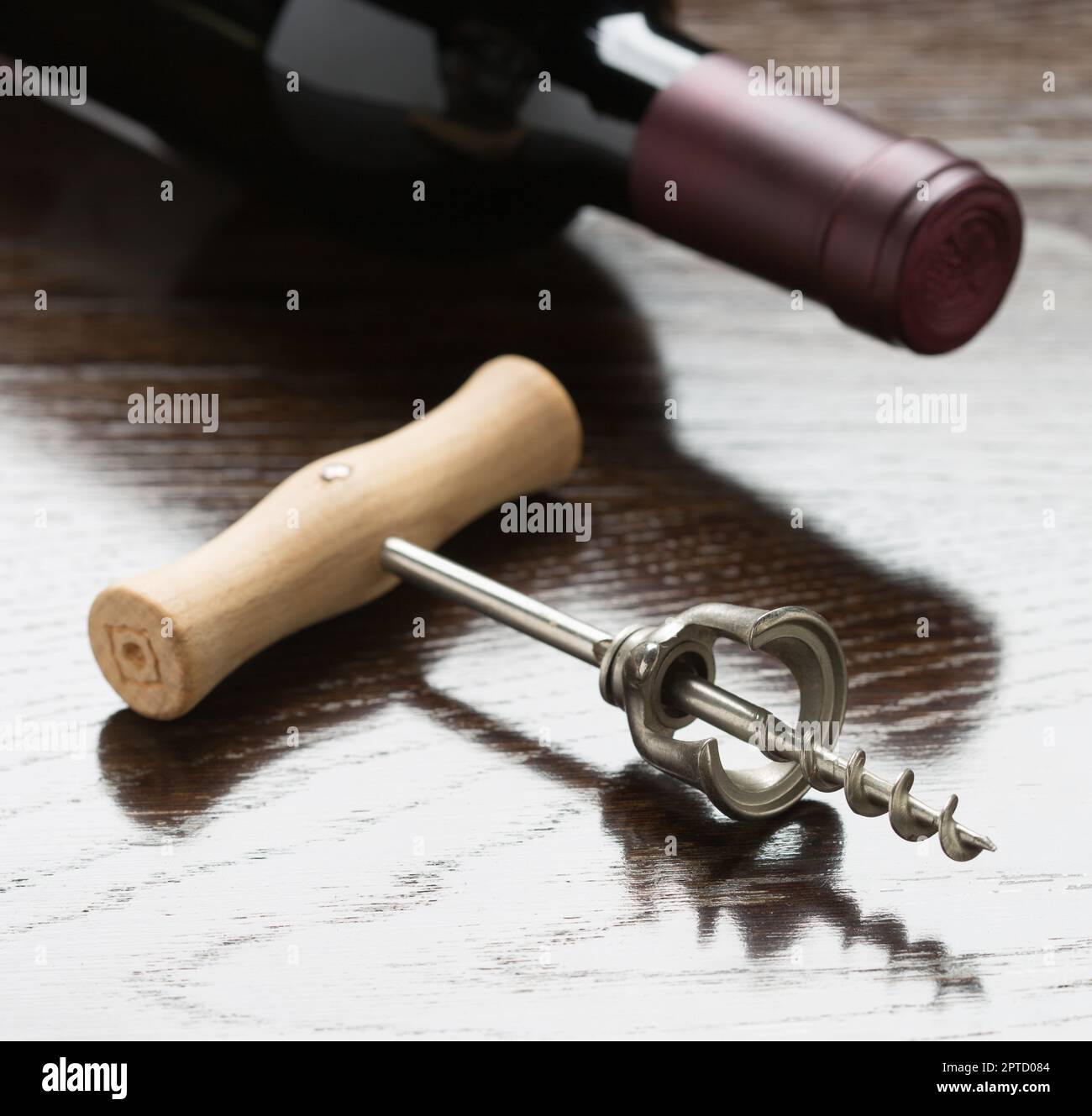 Abstract Wine Bottle and Corkscrew Laying on a Reflective Wood Surface