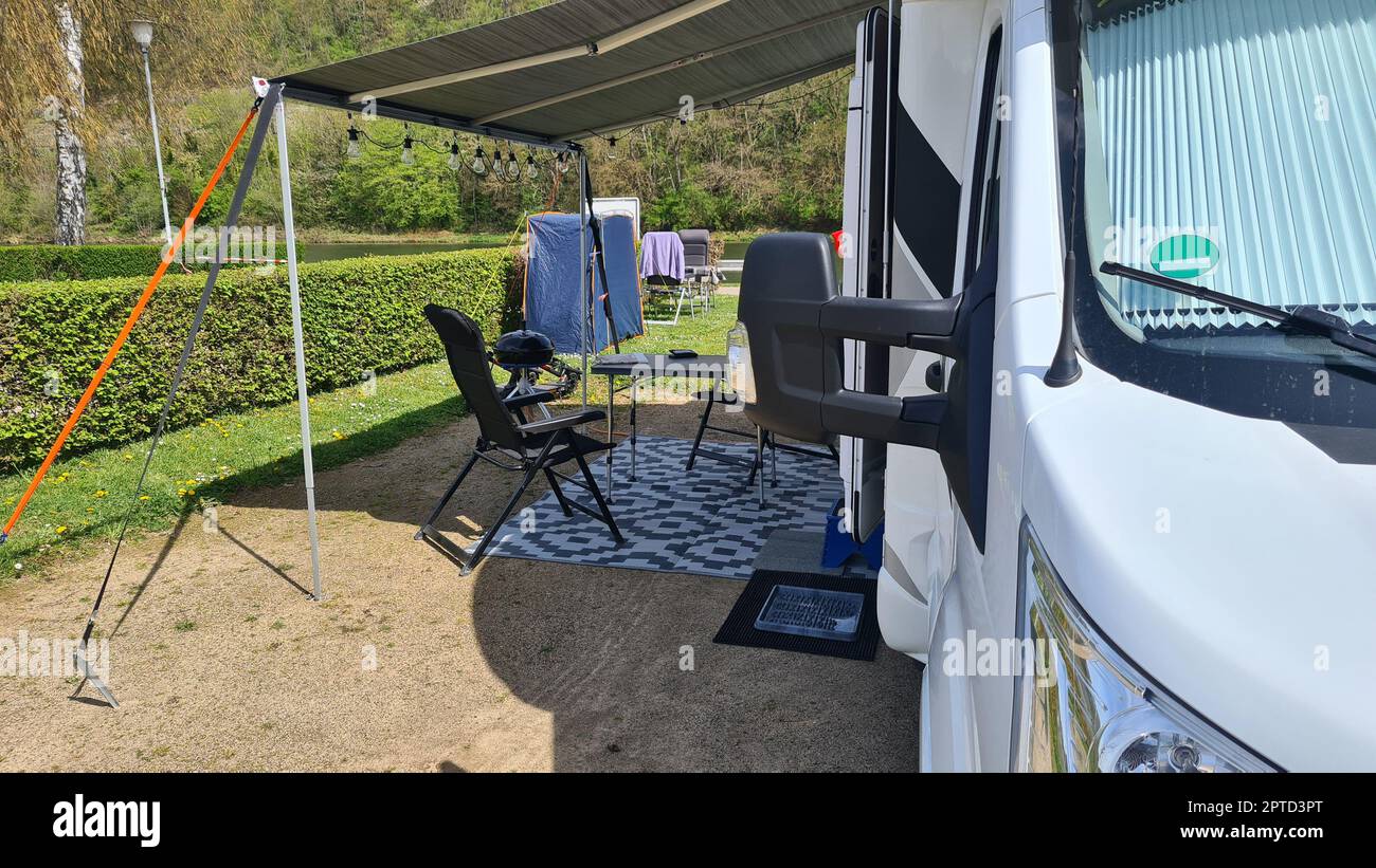 Campervan with awning and air awning and camping table with chairs at