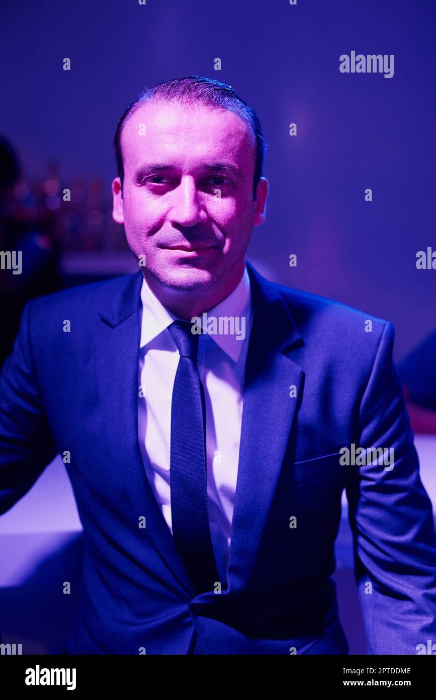 Headed to the club after work. Portrait of a shady businessman sitting in a seedy Thai nightclub Stock Photo