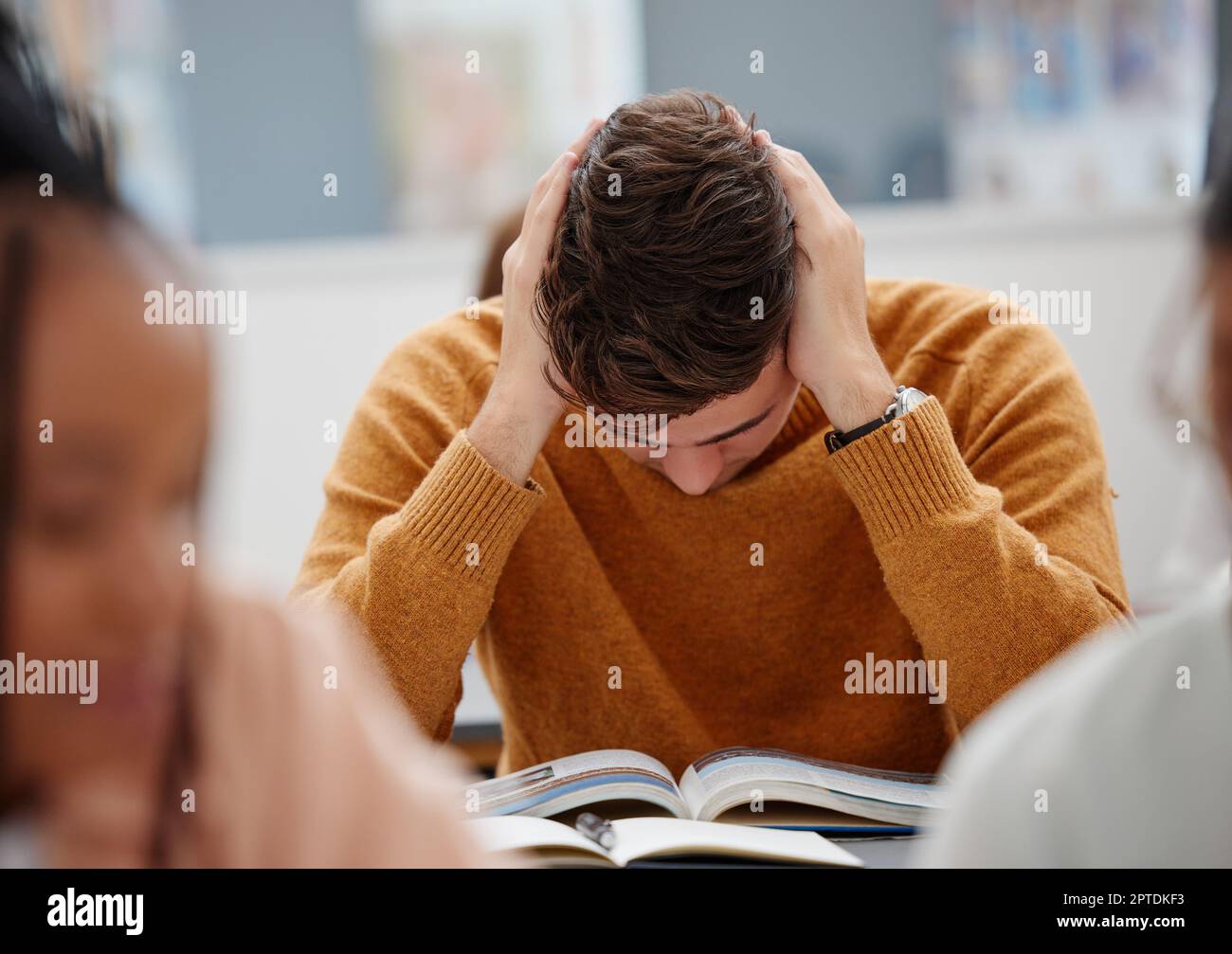 University, study and tired student reading book in class while studying for test or exam. Education, stress and burnout man with headache, knowledge Stock Photo