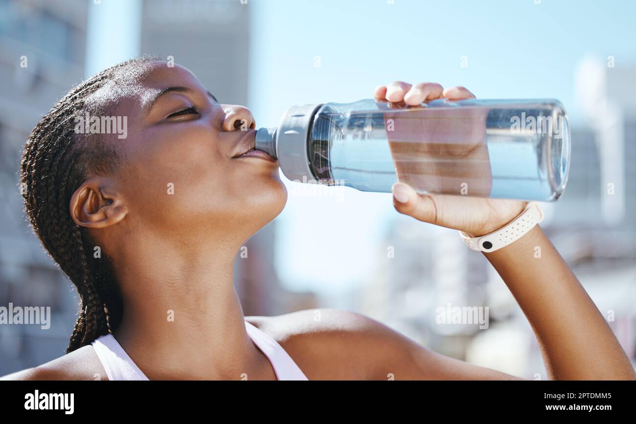 Water bottle, fitness and black woman outside in city for exercise