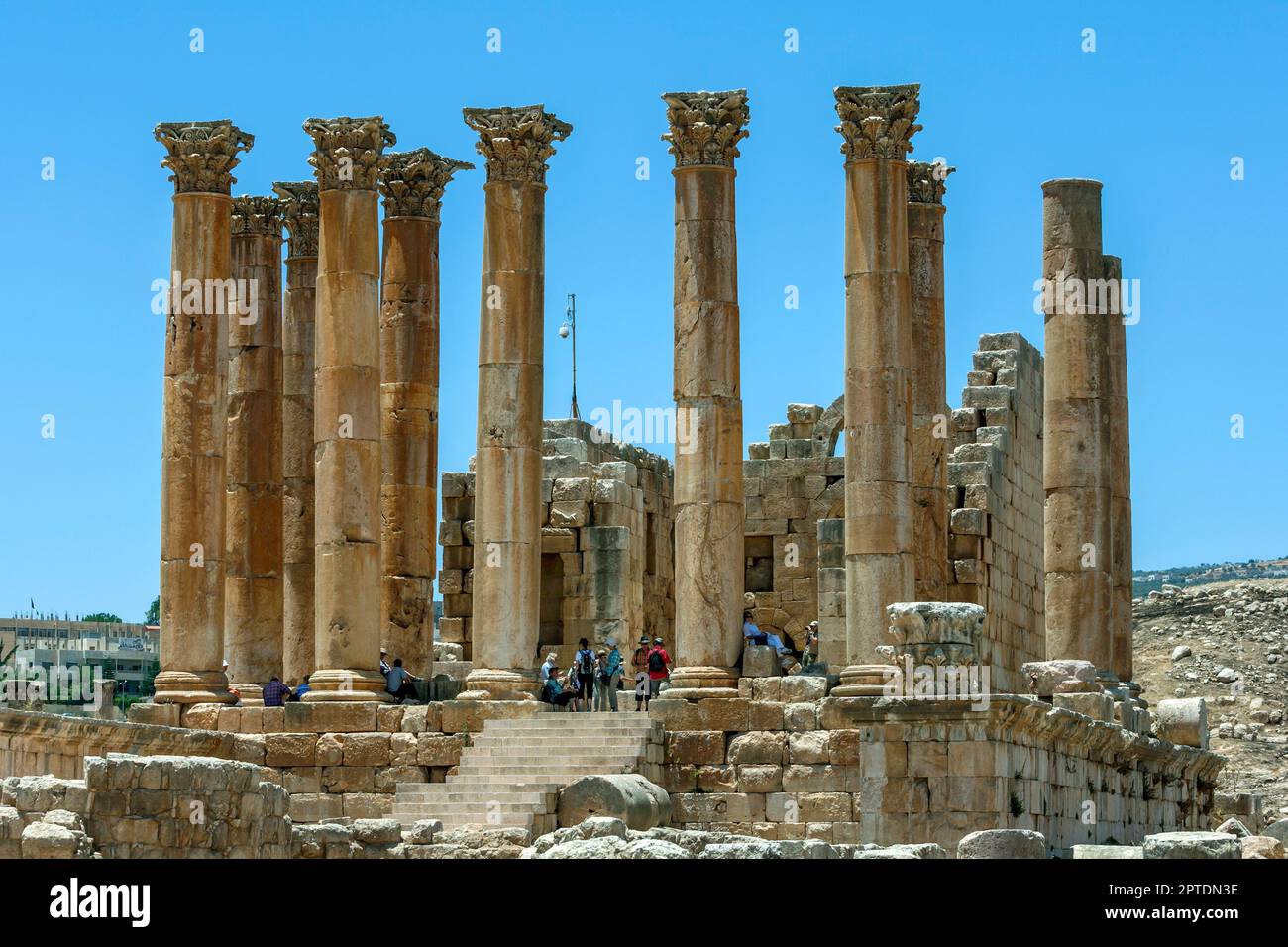 JARASH, JORDAN - JUNE 08, 2014 : Tourists gather at the base of the giant stone columns of the Temple of Artemis at the ancient site of Jarash in Jord Stock Photo