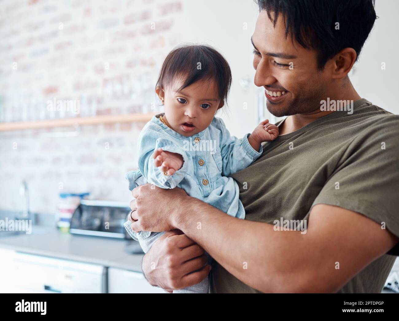 Down syndrome, baby and father bonding in their home with a proud parent caring for special needs infant in India. Love, family and child with happy m Stock Photo