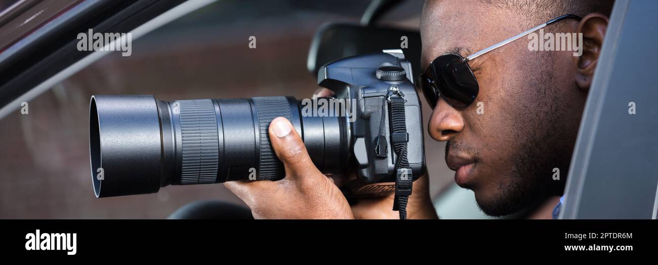 Private Spy In Car Taking Photos. African American Detective Stock