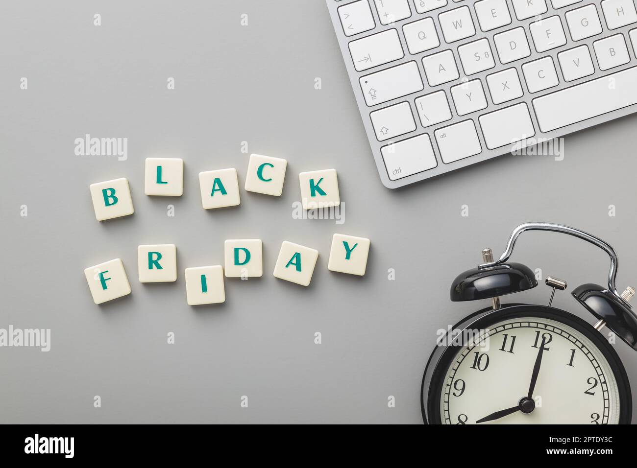 Black friday text, computer keyboard and alarm clock on the gray background. Top view. Stock Photo