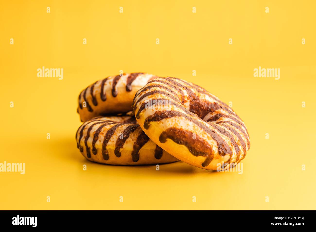 Donut with chocolate and caramel icing on the yellow background. Stock Photo