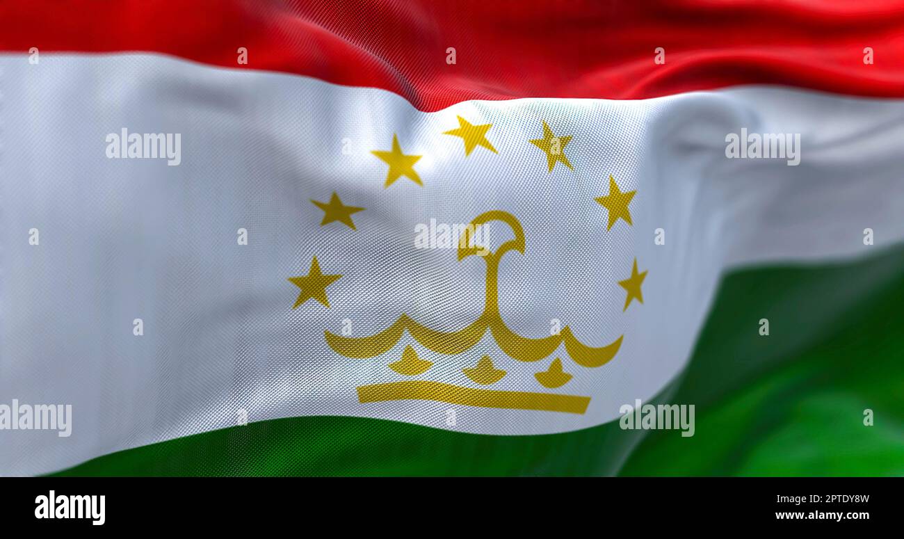 Close-up view of the Tajikistan national flag waving in the wind. The Republic of Tajikistan is a landlocked country in Central Asia. Fabric textured Stock Photo