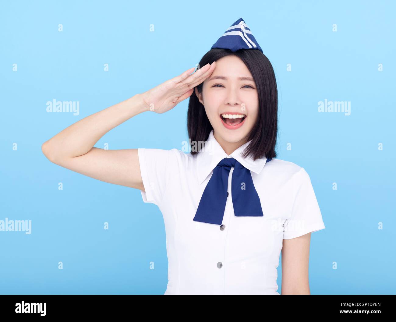 Happy young stewardess saluting isolated on blue  background Stock Photo