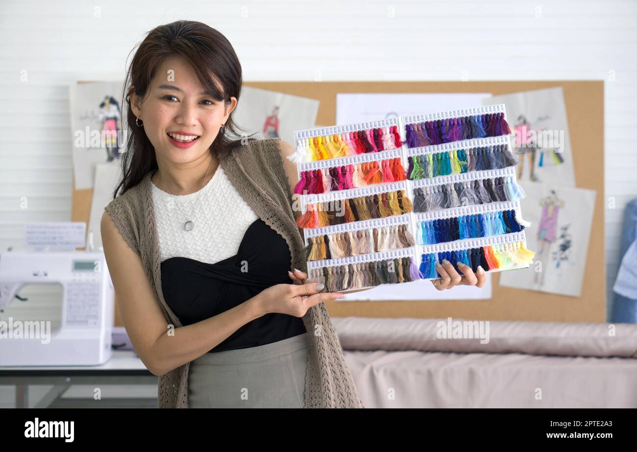 Fashion designer room. Young asian dressmaker present silk thread color