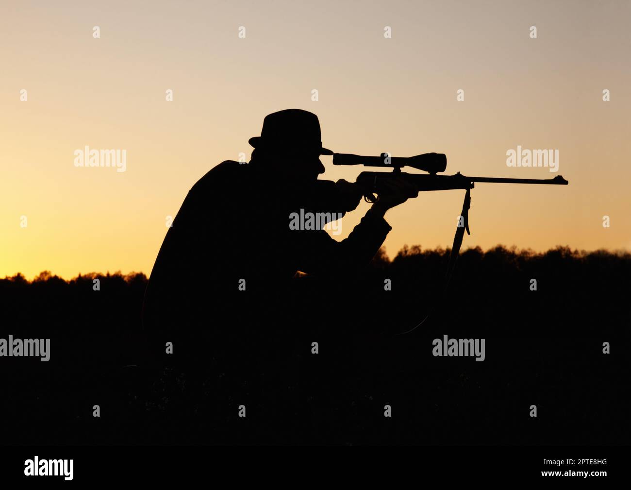 Hunting the hunter. A silhouette of a man in the outdoors holding up his sniper rifle Stock Photo