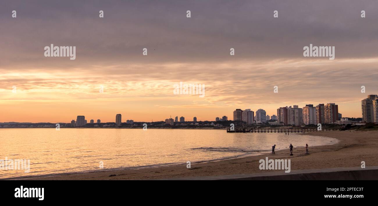 Sunset over Mansa beach in Maldonado bay, with some apartment buildings on the horizon Stock Photo