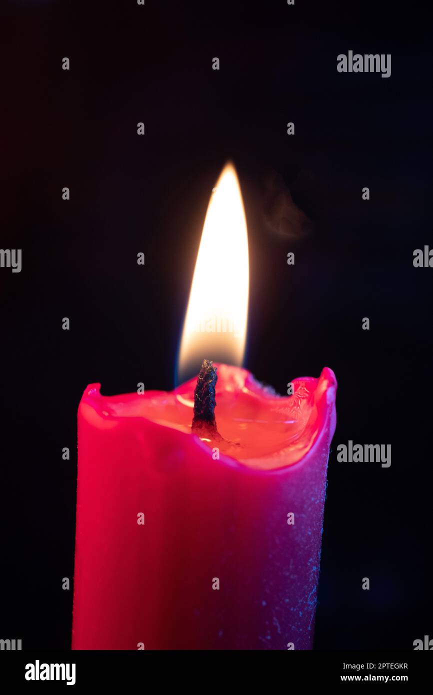 Candle flame flickers in the wind against a black background Stock
