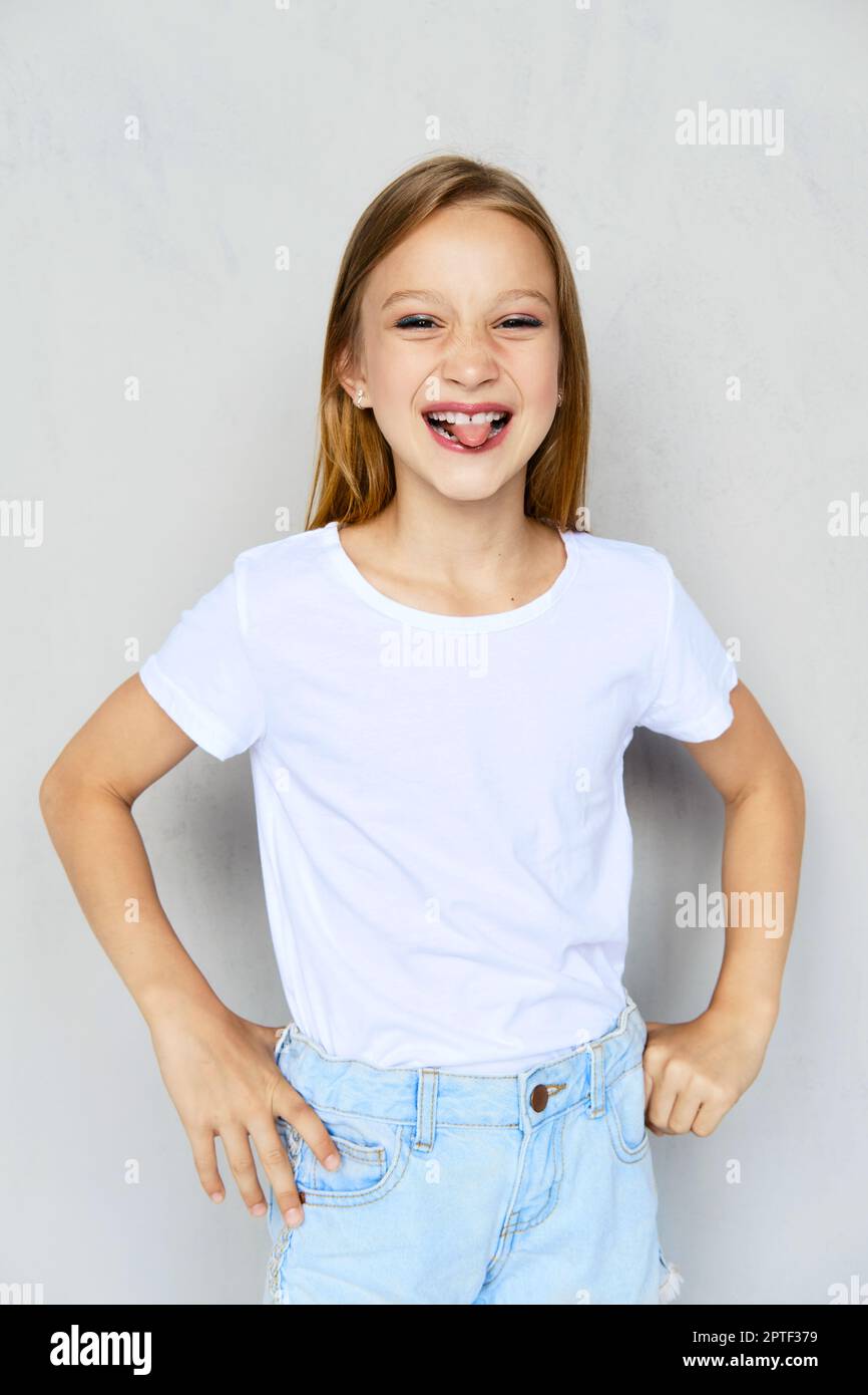 Free Photo  Funny young girl in white t-shirt looking at camera sticking  out tongue and winking standing over blue background