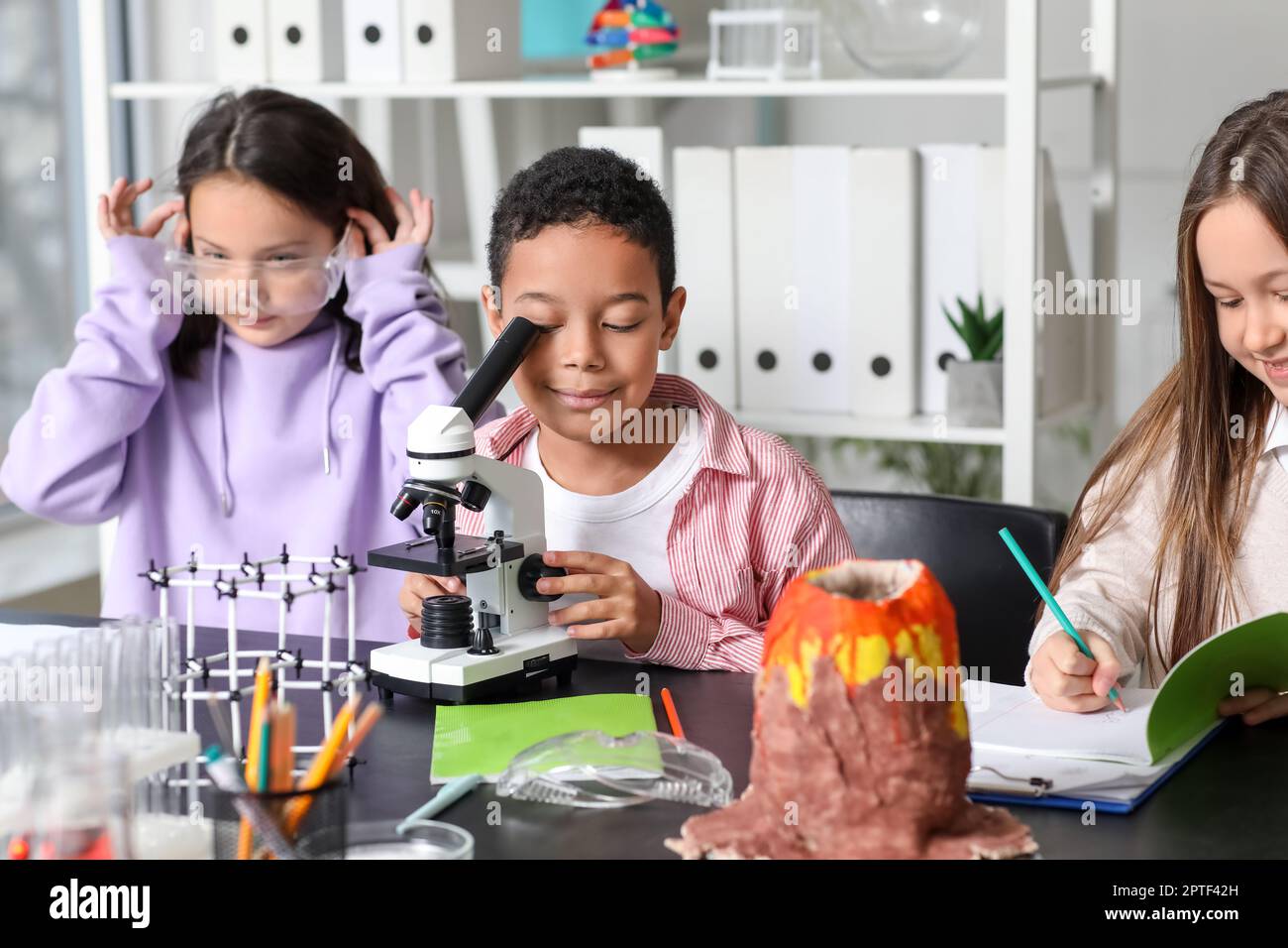 Little children with microscope studying chemistry in science classroom ...