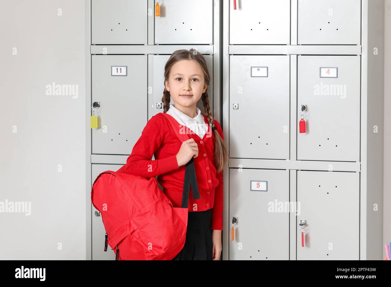 Little girl with backpack near locker at school Stock Photo Alamy