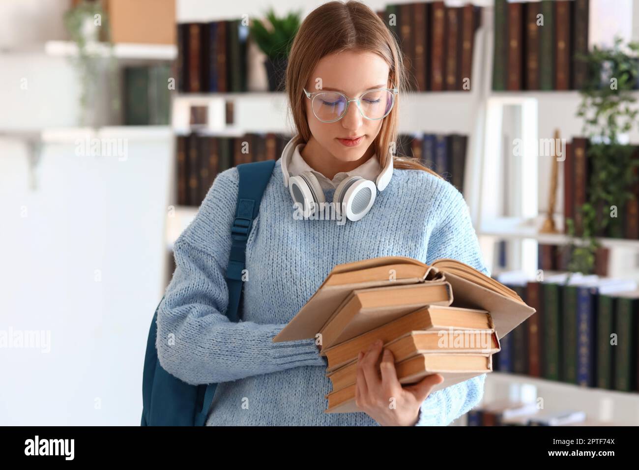 Female student with books in library Stock Photo - Alamy