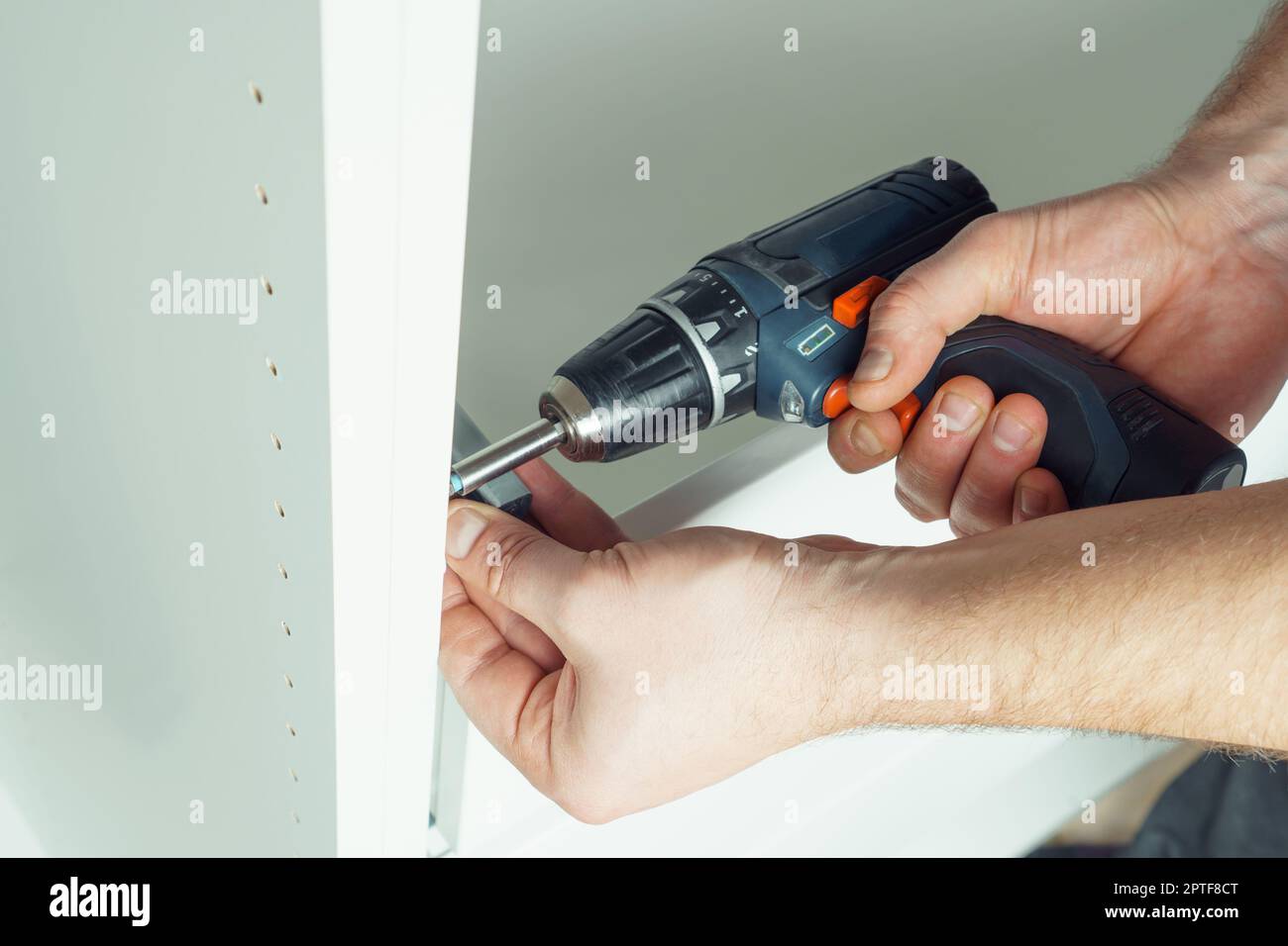 Male hands hold cordless electric screwdriver, screw to fix rail ...