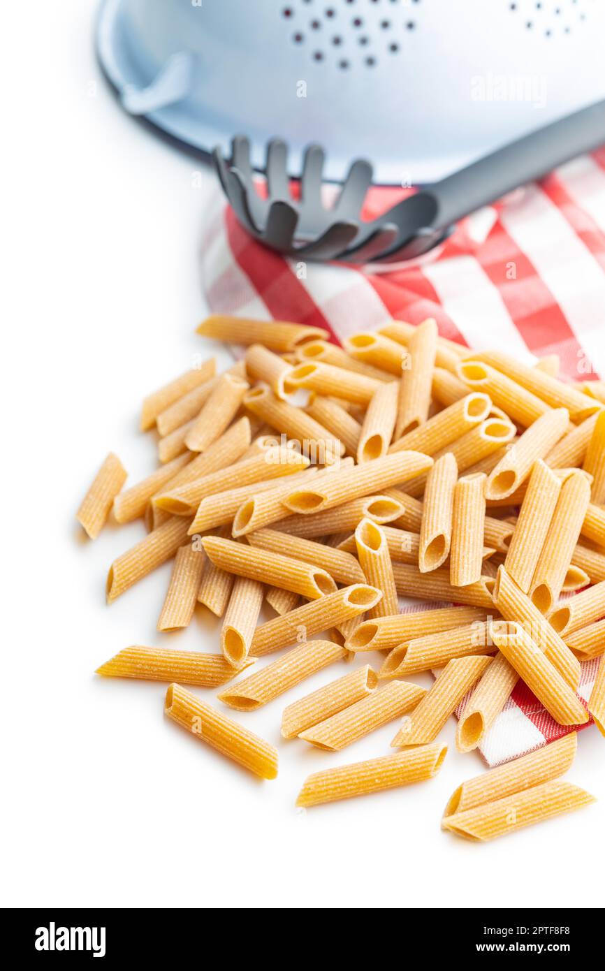 Uncooked whole grain pasta isolated on the white background. Raw penne pasta. Stock Photo