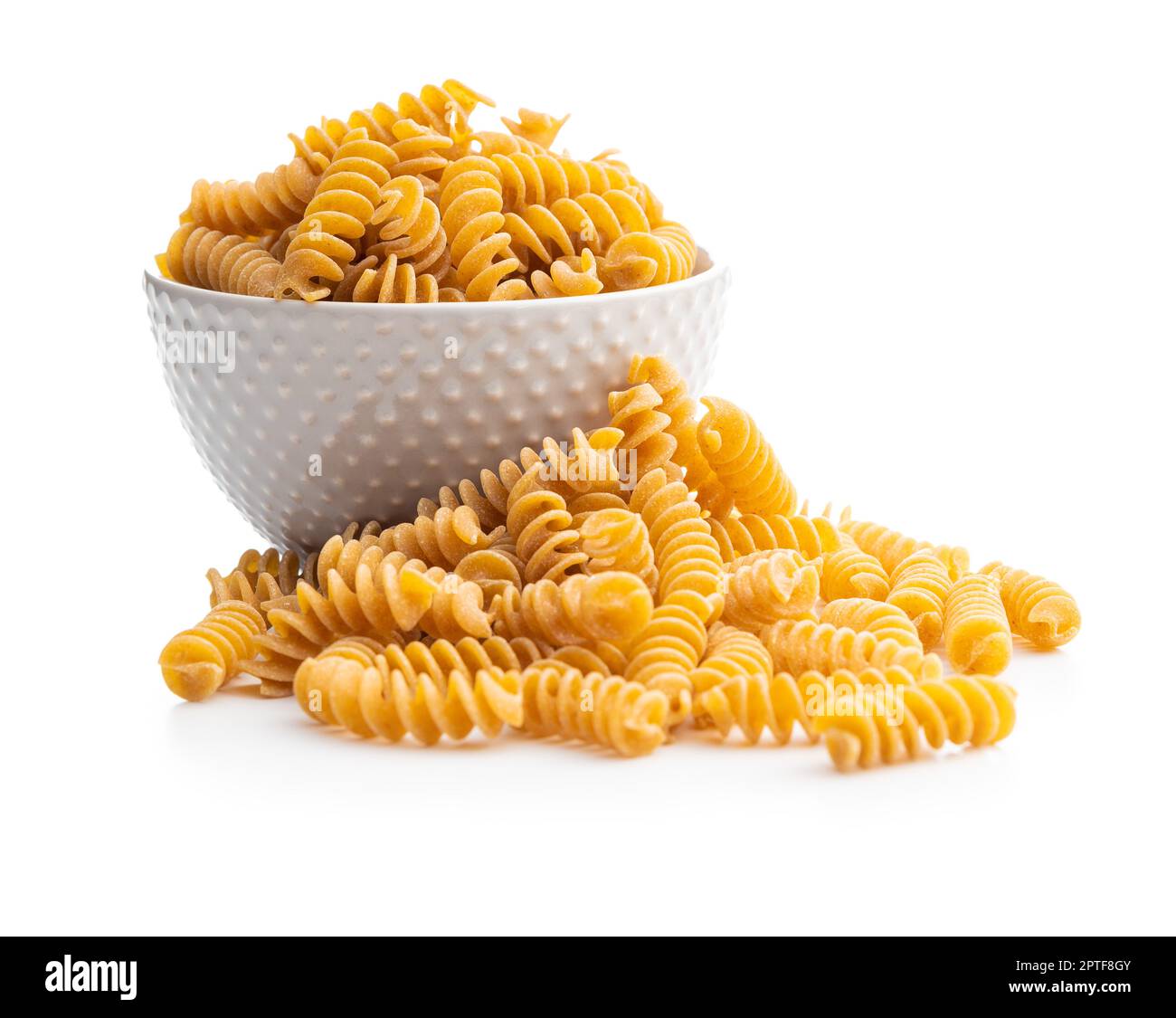 Uncooked whole grain pasta isolated on white background. Raw pasta in the bowl. Stock Photo
