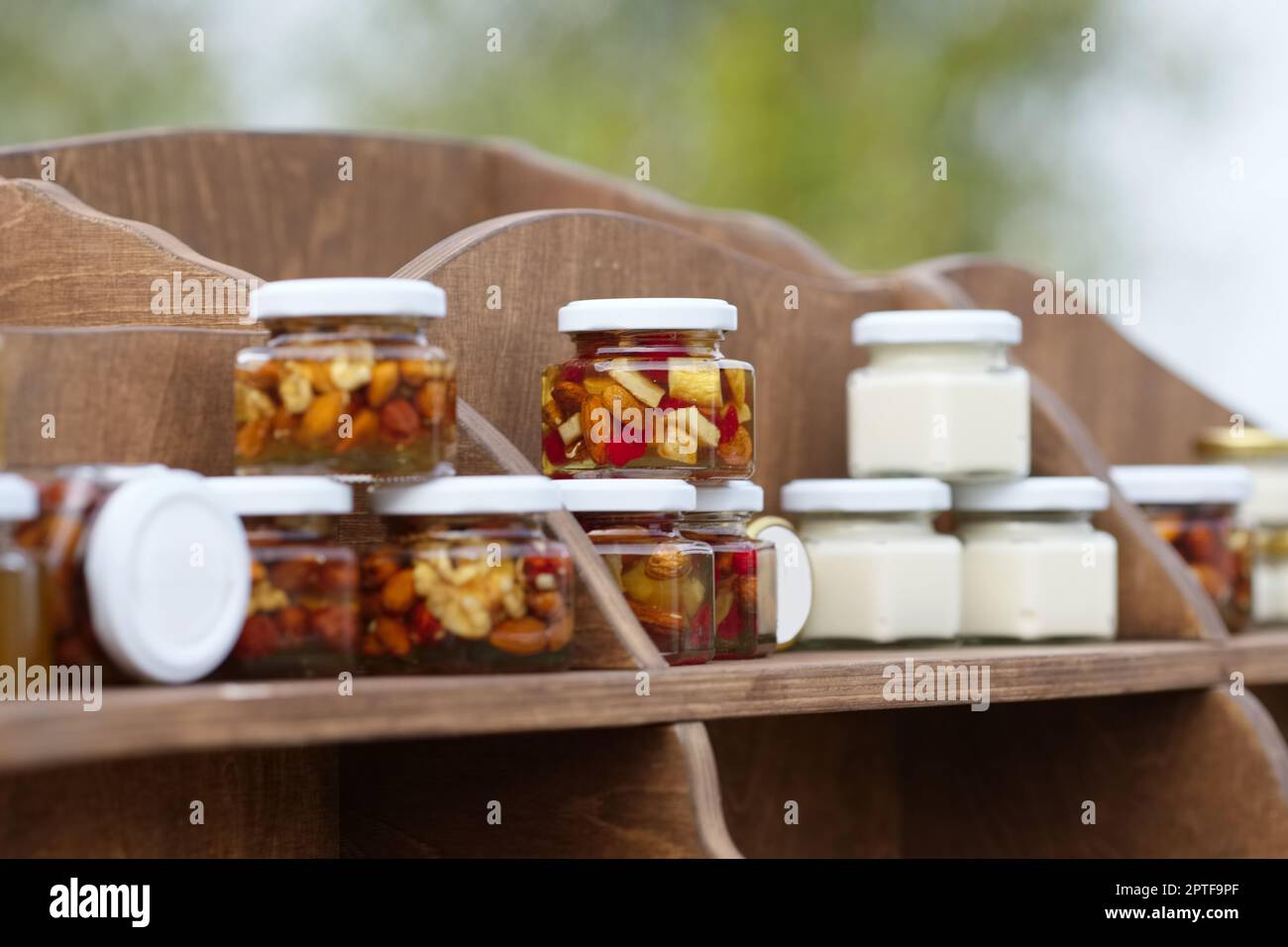 Nuts and honey in small jars on shelf Stock Photo