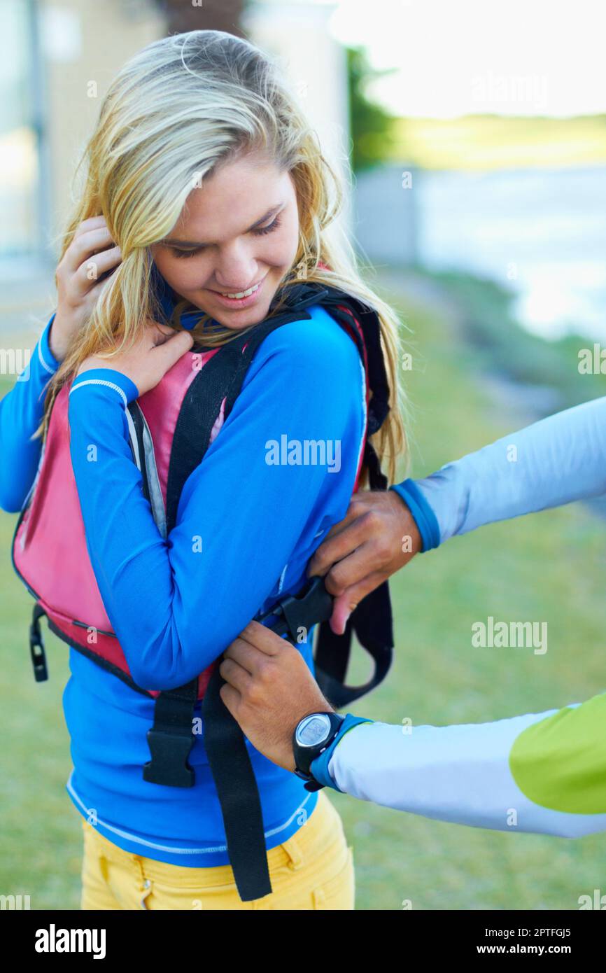 Making sure shes safe. an attractive young woman getting some assistance with her life jacket Stock Photo