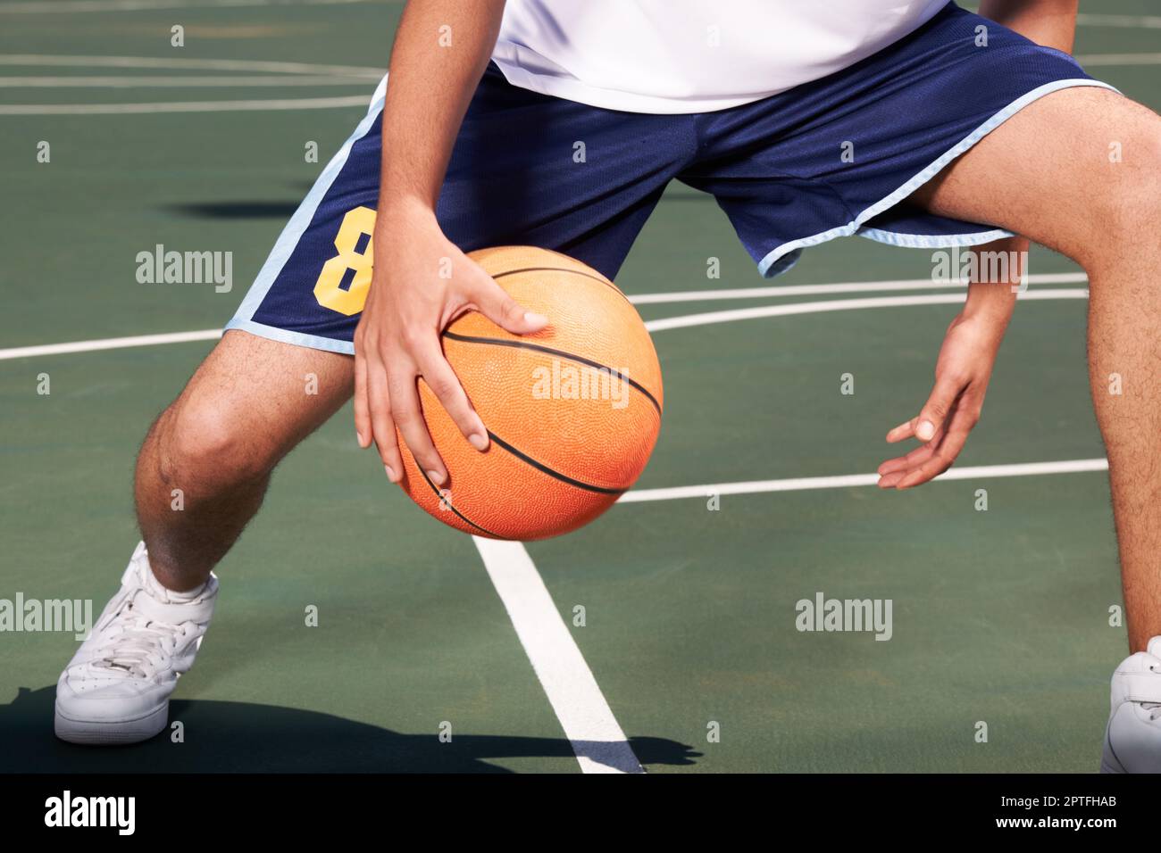 Check out this cool pass. A basketball player passes the ball between his legs Stock Photo