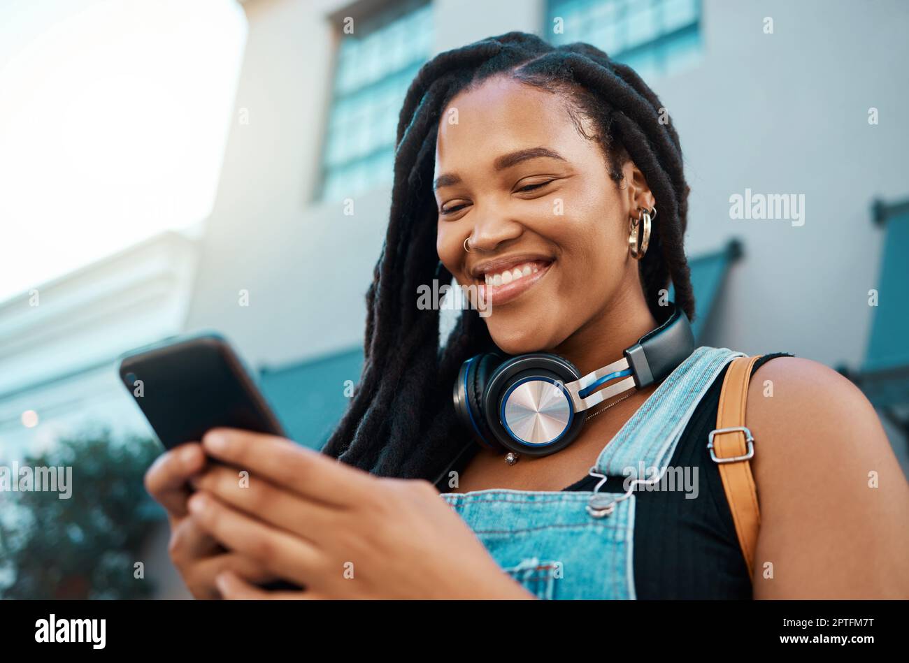 Black woman with a phone in the city, search for online podcast or radio,  happy looking for music to listen to. Freedom, relax and smile by African  Am Stock Photo - Alamy