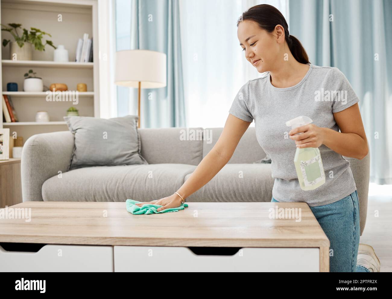Cleaning table, bottle and Asian woman working to keep her living room