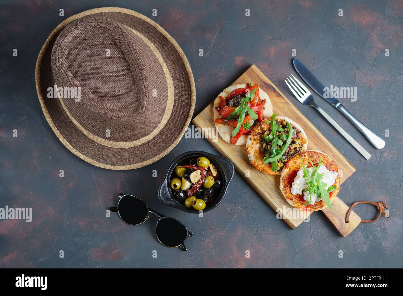 Delicious tapas set. Small sandwiches with goat cheese, chopped olives and nuts, cured tomato and roasted bell pepper. Stock Photo