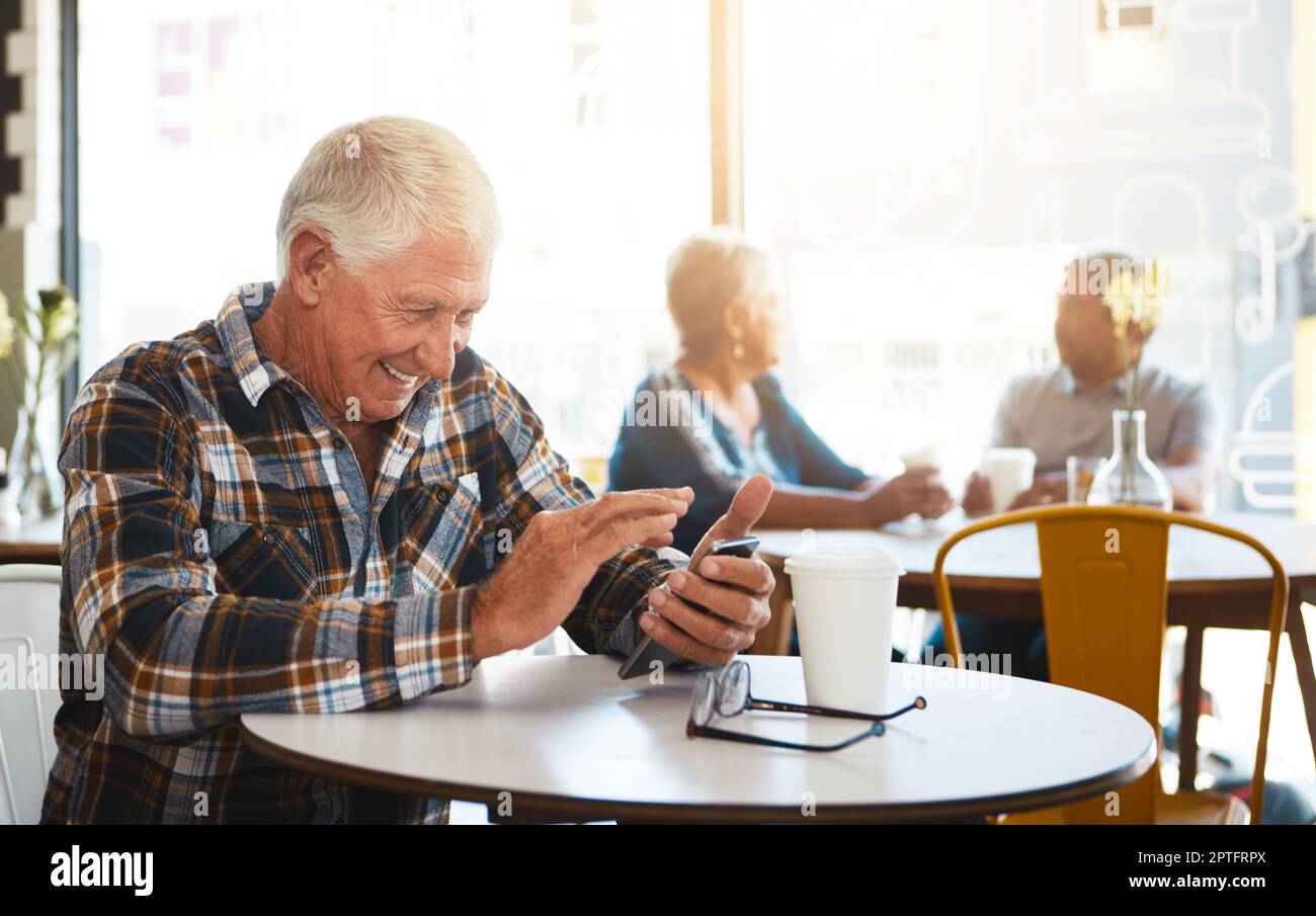 Sharing a giggle with the one I love. a senior man using his phone in a cafe. Stock Photo