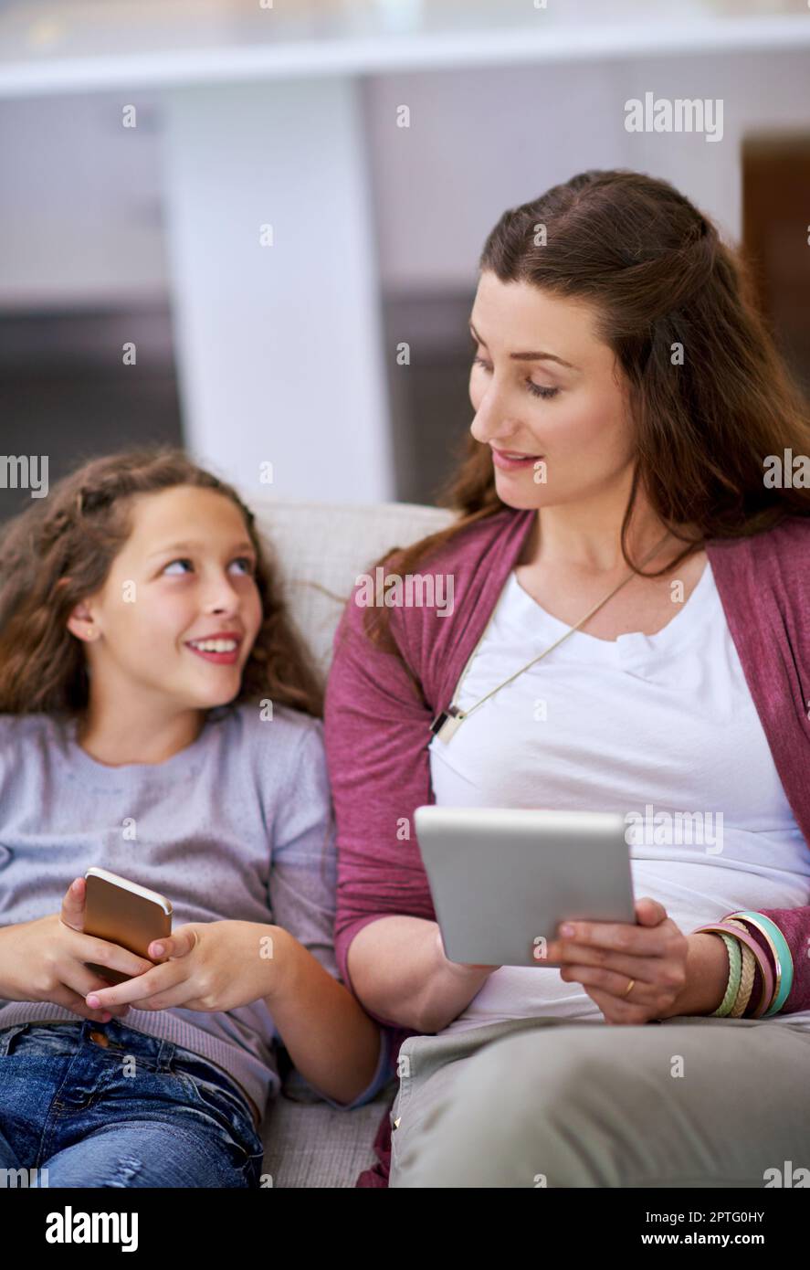 I just got ANOTHER friend request. a young girll and her mother sitting on the sofa and using their smart devices Stock Photo