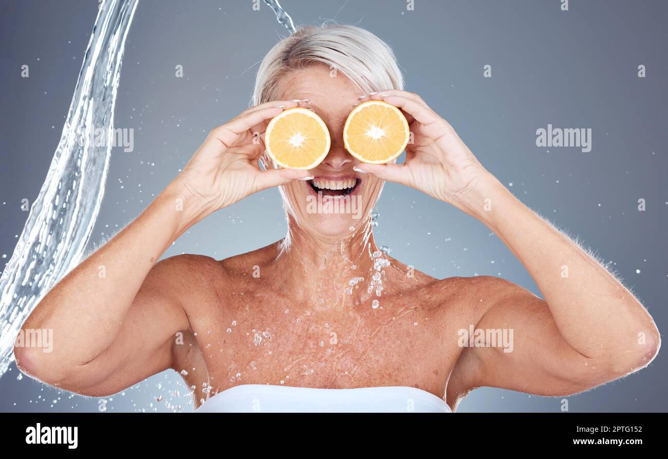 Water splash, fruit and senior skincare of a woman holding orange for