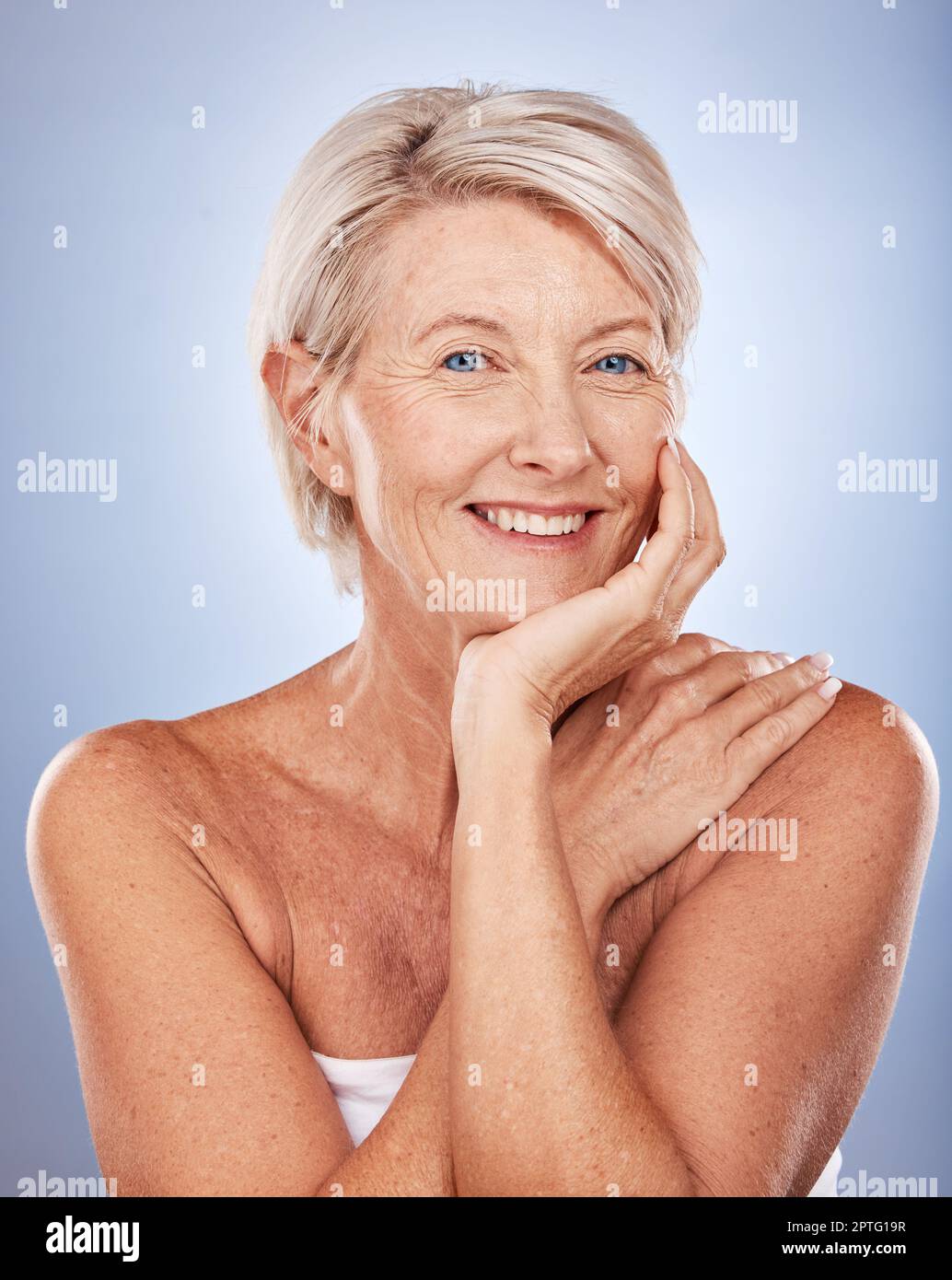 Beauty, skincare and portrait of mature woman with smile on face on blue background. Health, wellness and retirement, happy senior lady with skin care Stock Photo