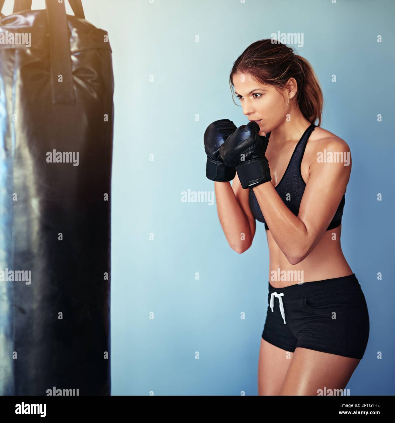 Fighting her way to fitness. a female boxer working out with a punching ...