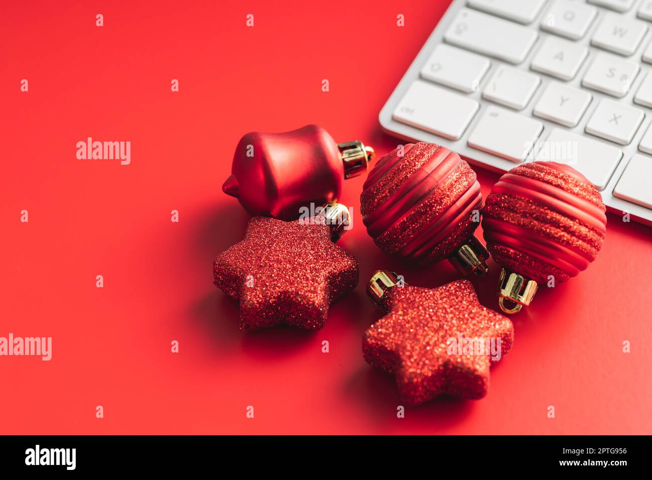 Red christmas decoration. Christmas bulbs and computer keyboard on the red background. Stock Photo