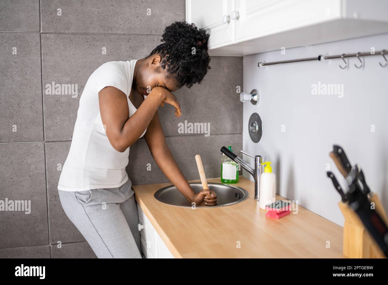 Cleaning Blocked Sink And Drain In Kitchen Using Plunger Stock Photo