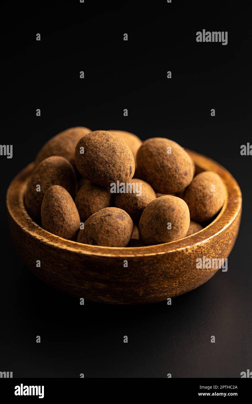 Almonds in chocolate coated in cocoa in bowl on a dark table. Stock Photo