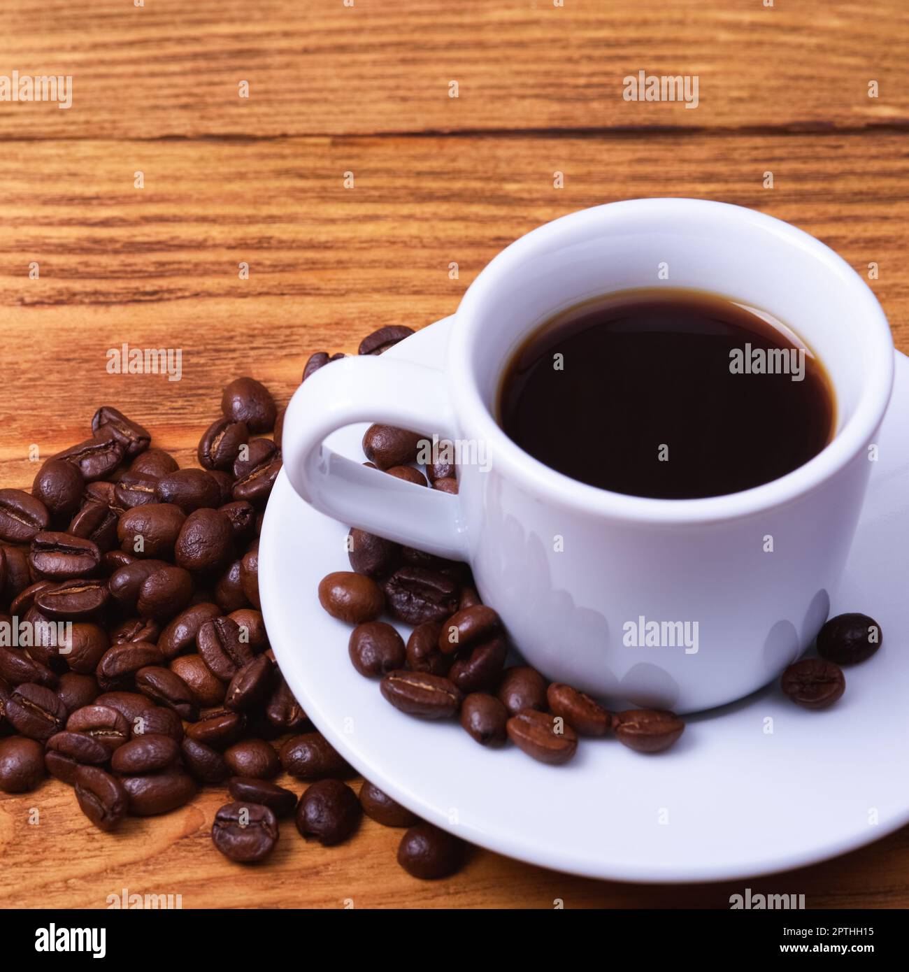 Freshly made coffee in a white Cup on a white saucer surrounded by  scattered coffee beans on a wooden table. Fresh roasted coffee. Place for  an inscri Stock Photo - Alamy