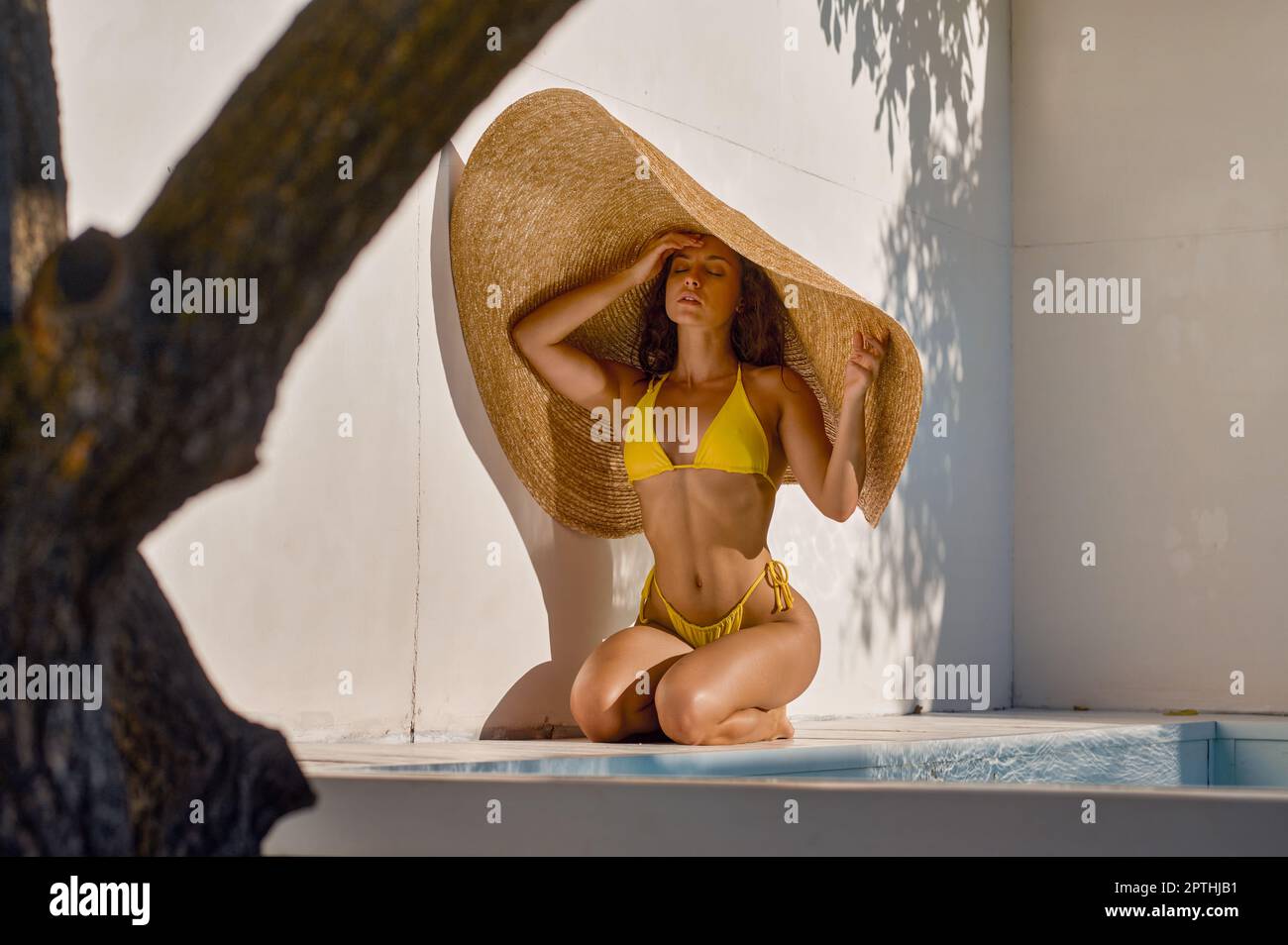 Attractive woman hiding from hot sun under big fashion straw hat