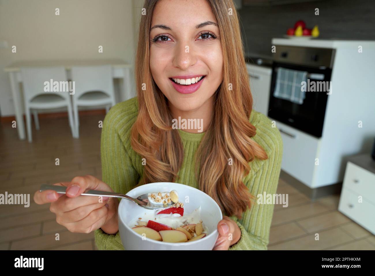 Young woman eating muesli granola oatmeal with fruits and yogurt