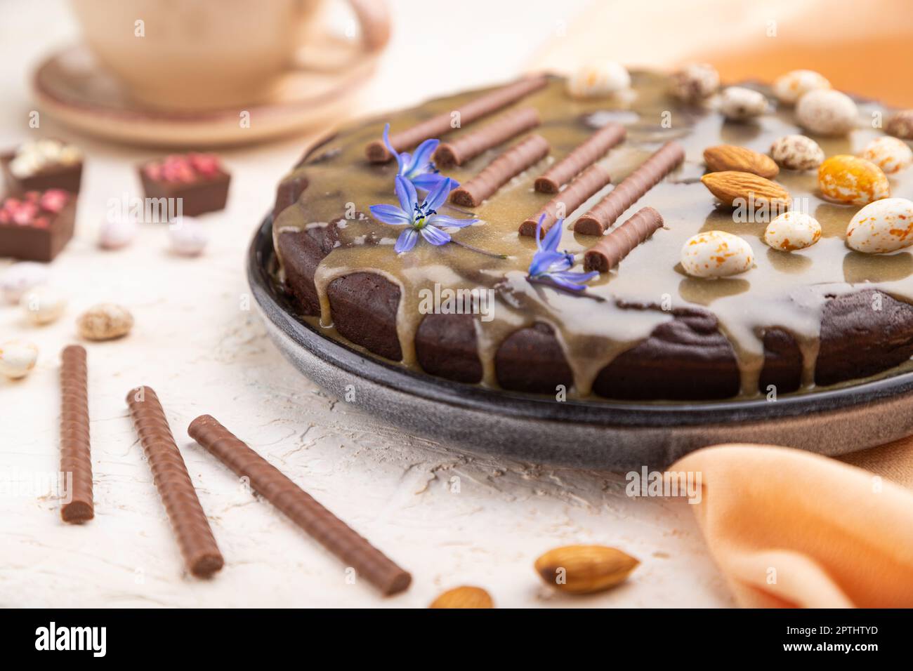 Homemade chocolate brownie cake with caramel cream and almonds with cup of coffee on a white