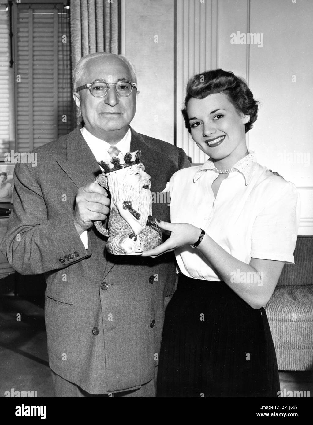 MGM Studio Head LOUIS B. MAYER in 1950 receiving gift at MGM Culver City Studios from British beauty SYLVIA WREN (winner of the Neptune's Daughter contest held at Prestatyn Holiday Camp in Wales) during her 10 day trip to Hollywood publicity for Metro Goldwyn Mayer Stock Photo