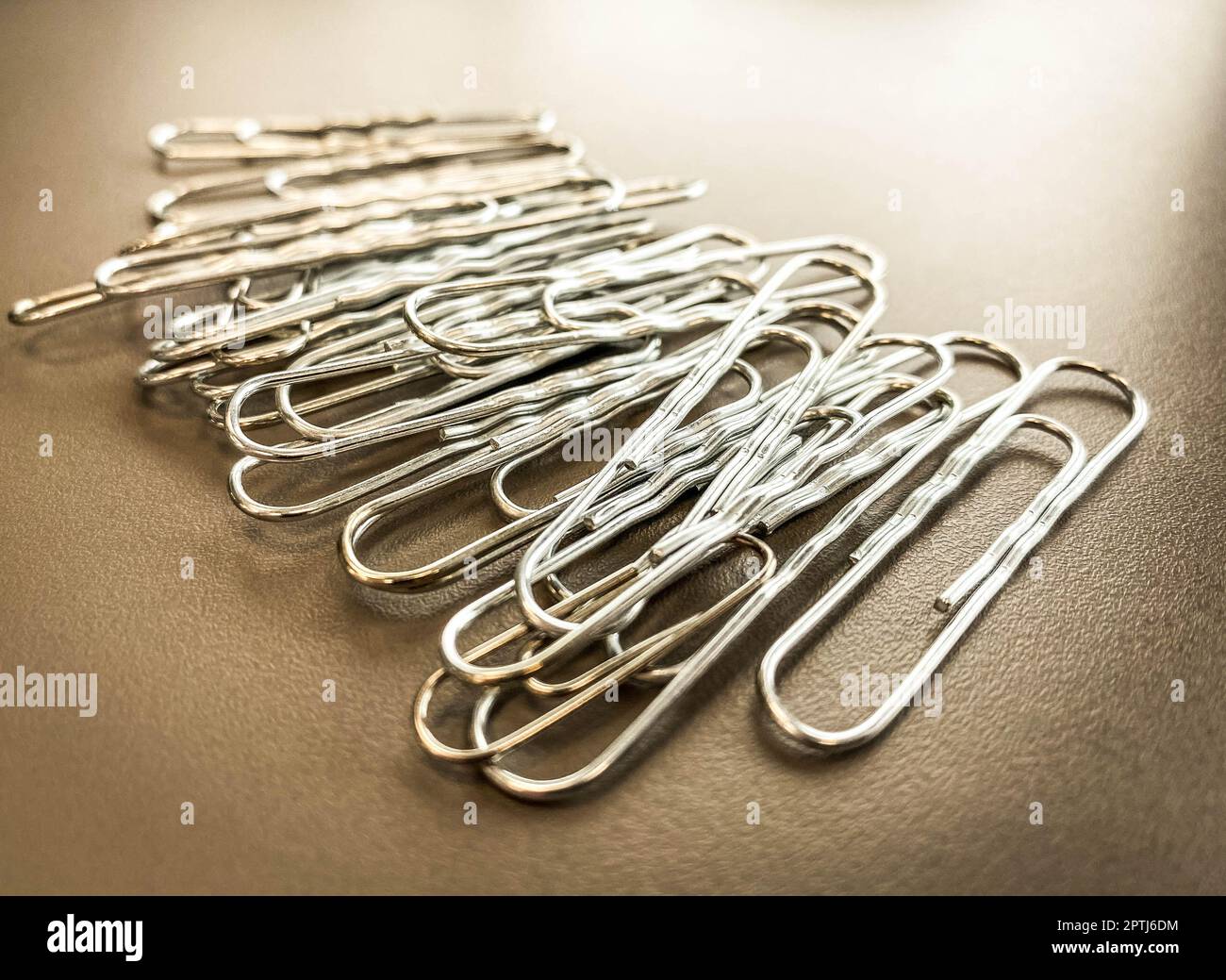 metal paper clips lie on a dark, matte background. paper binding tool