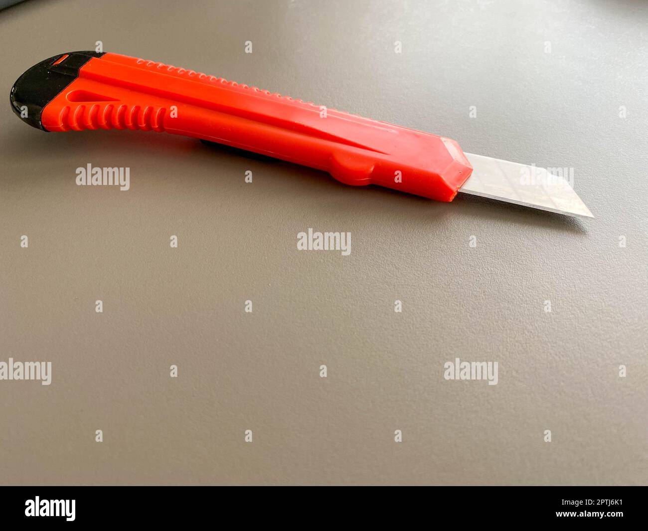 Red sharp office stationery knife with a paper cutting blade on a