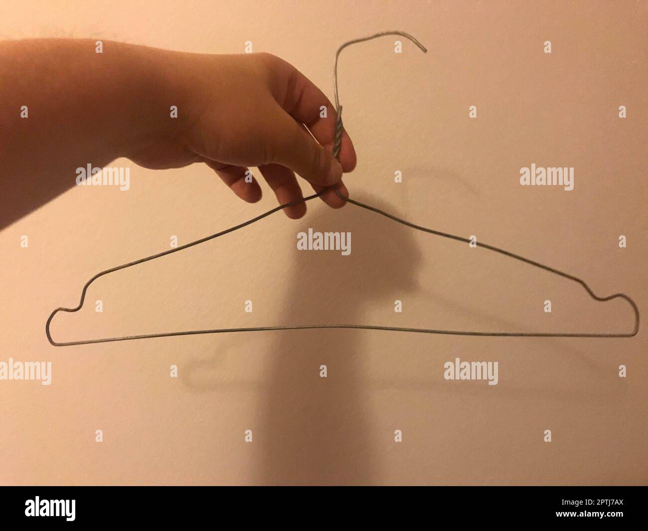 Homemade clothes hanger made of wire. Poor clothes rack in a cheap hotel room. Stock Photo